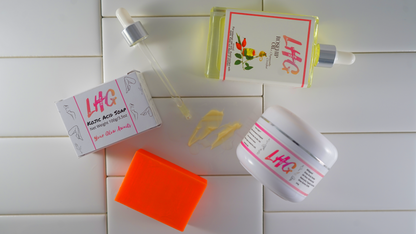 LHG skincare products including a jar, soap, and packets on a white tiled background texture products.