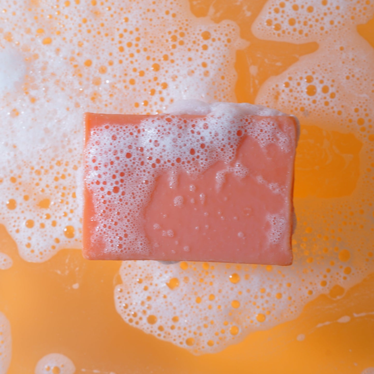 Deep orange soap bar with bubbles on a yellow background