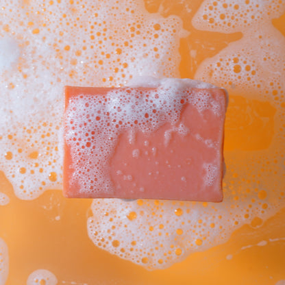 Deep orange soap bar with bubbles on a yellow background